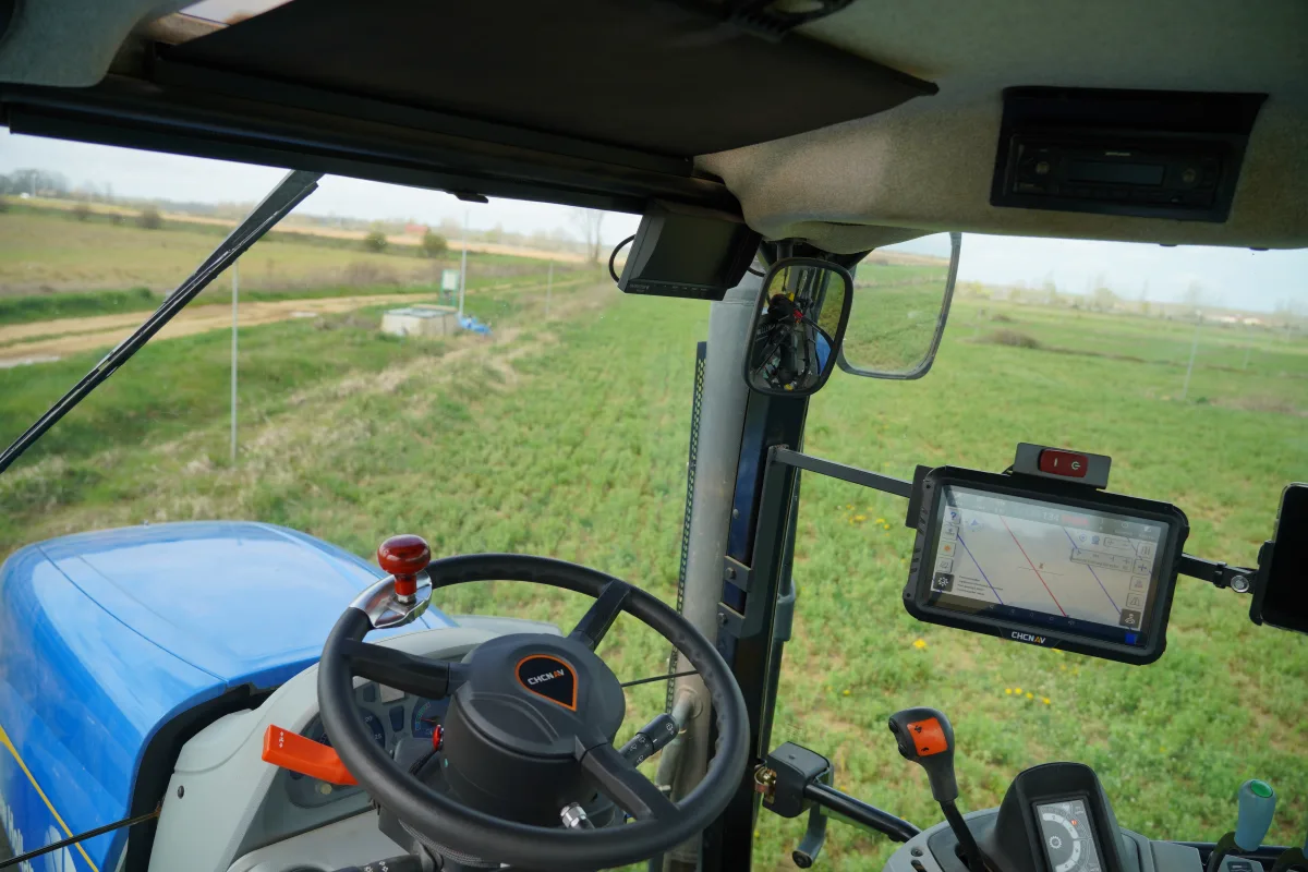 CHCNAV electric steering wheel and NX510 display installed in a New Holland tractor cab overlooking a green field