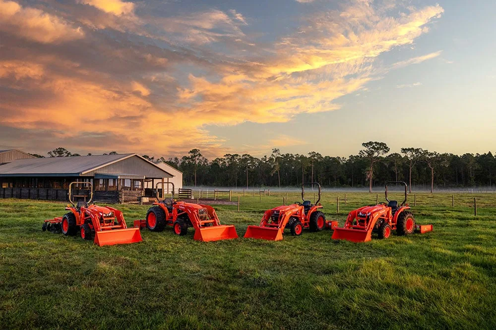 Four Kubota Standard L02 Series tractors with loaders, including the L2502, lined up in a field at sunset