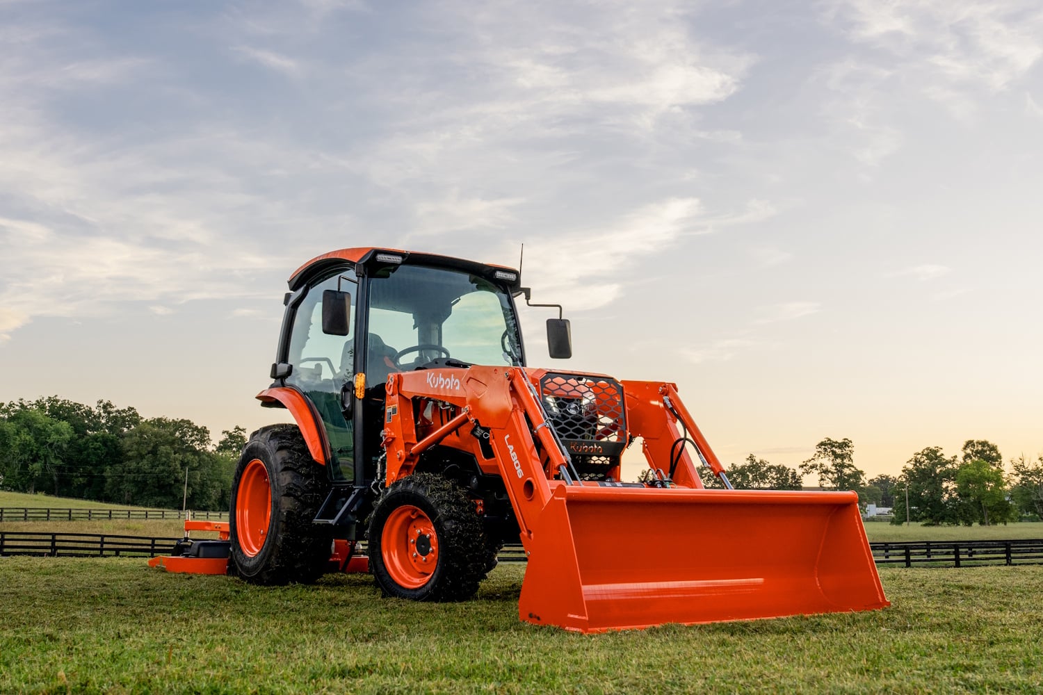 Kubota L tractor mowing a field