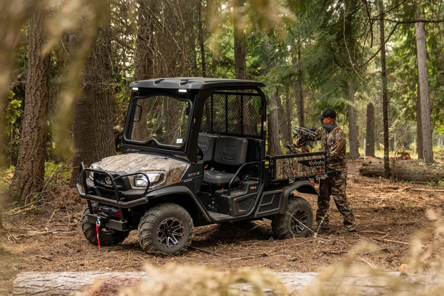 Kubota RTV-X utility vehicle in Realtree camo parked in the woods while a hunter loads gear