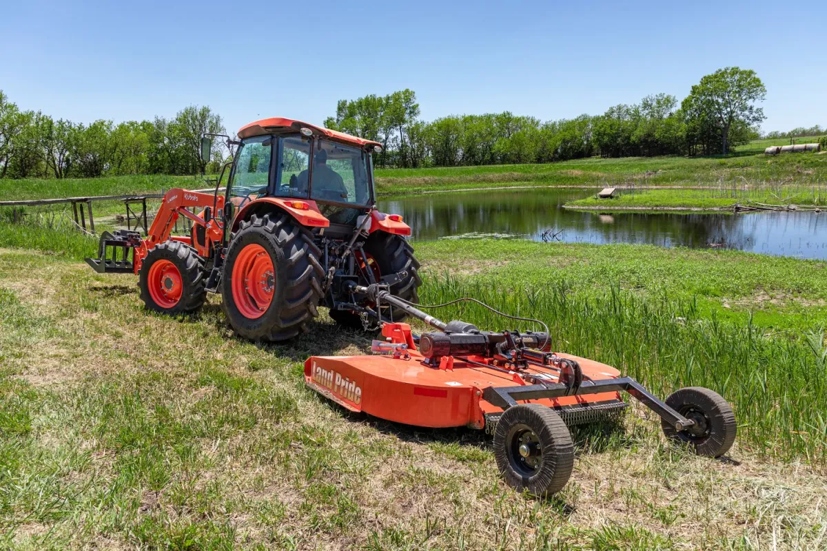Kubota M-Series tractor running a Land Pride rotary cutter in a field