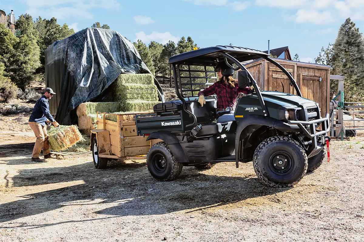 Kawasaki MULE SX utility vehicle towing a hay trailer at a ranch