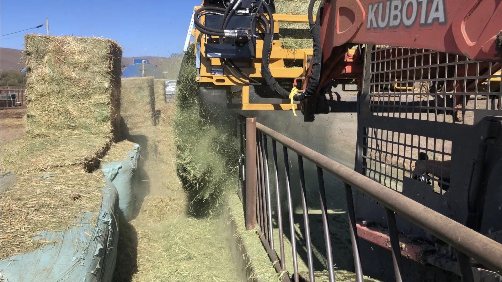 Tubeline Bale Boss I-3820 processing a large square bale beside a feed bunk