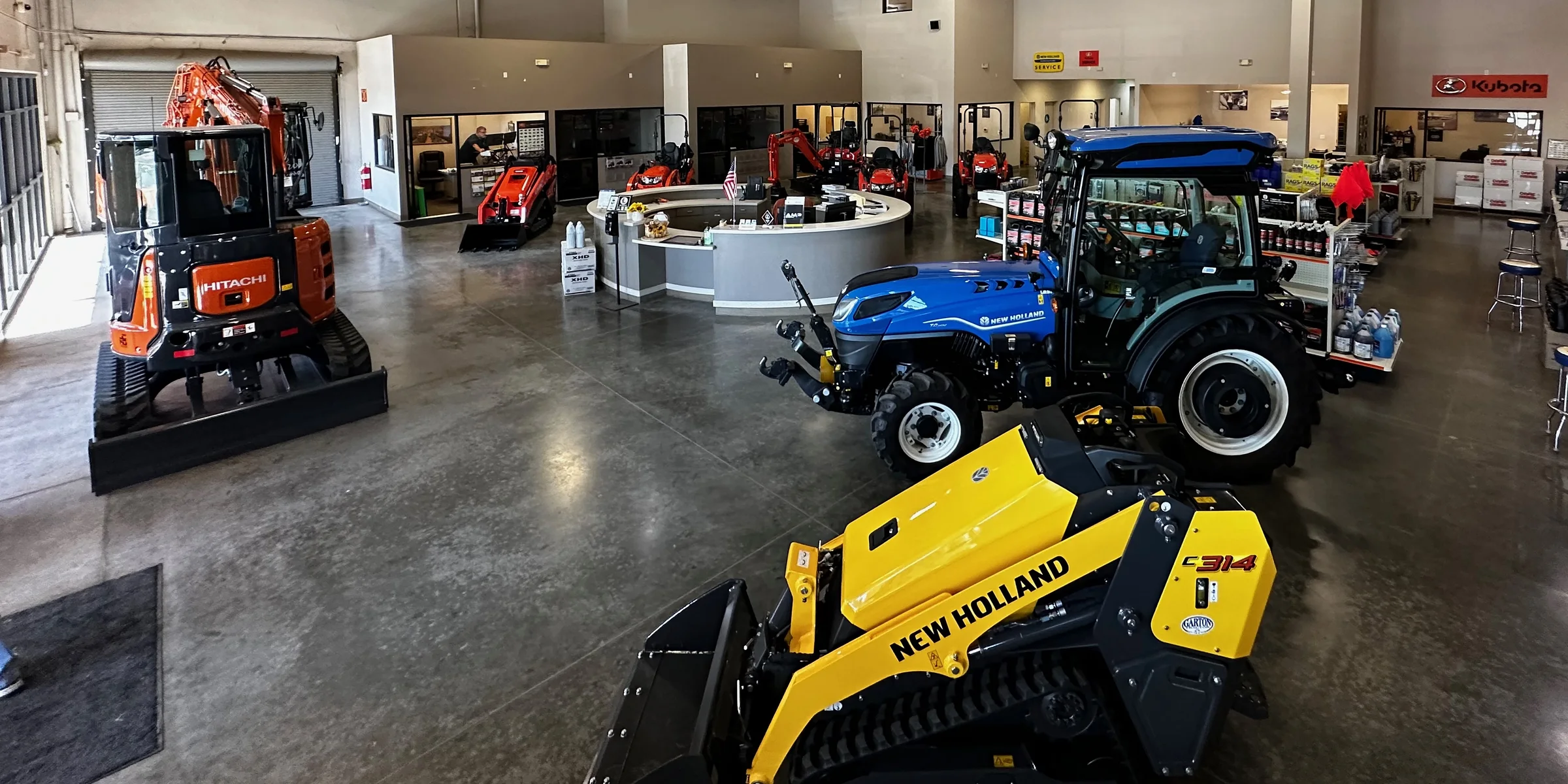 Kubota, Hitachi, and New Holland equipment inside a Garton Tractor showroom